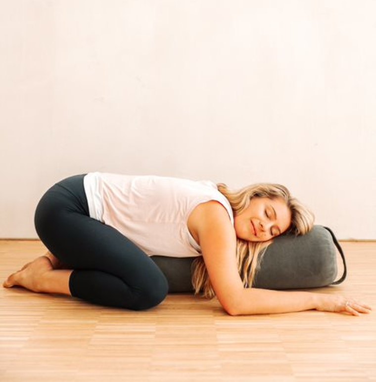 Alexandria resting over a bolster in a restorative pose